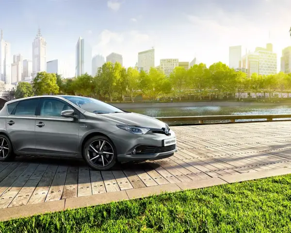 Szary Toyota Auris Hybrid na drewnianym pomoście, z miastem w tle. Jaki olej do tego modelu?