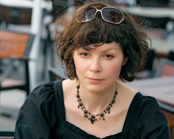 Agnieszka Glińska w czarnej sukience i naszyjniku, z okularami na głowie. Może wspominać swoich rodziców.