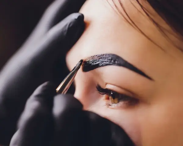 Stylist nakłada hennę pudrową na brwi. Zastanawiasz się, ile kosztuje henna pudrowa?