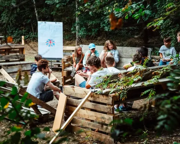Kinder lernen im Freien beim englisch camp. Eine Tafel mit der britischen Flagge steht im Hintergrund.