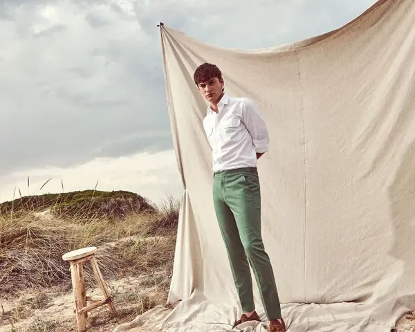 Un uomo con camicia bianca e pantalone verde, un look perfetto per l'estate. Scopri come abbinare un pantalone verde per un outfit fresco e alla moda.