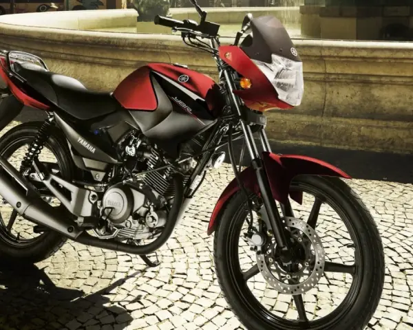 Czerwony motocykl Yamaha YBR 125 na brukowanej ulicy. Sprawdź yamaha ybr 125 dane techniczne, by poznać jego możliwości.