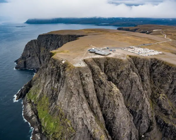 Majestatyczne klify na Nord Kapp, z widokiem na ocean i budynkami turystycznymi.