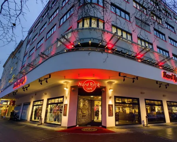 Das Hard Rock Cafe Berlin erstrahlt im Abendlicht. Rote Neonschilder und Beleuchtung werfen einen warmen Schein auf die Fassade des Gebäudes.