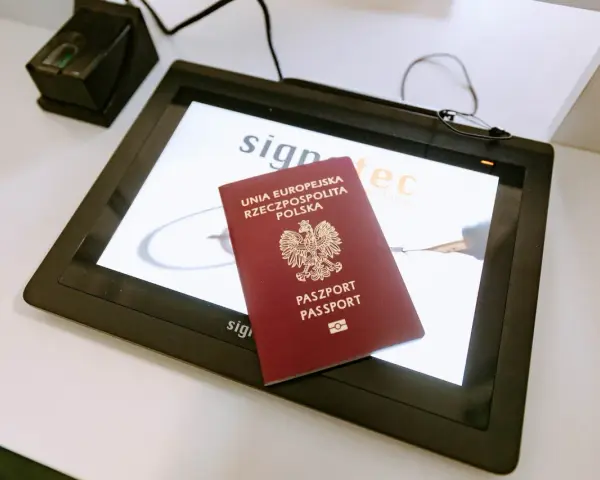 Polski paszport na ekranie tabletu w biurze paszportowym Włocławek. Obok skaner linii papilarnych.