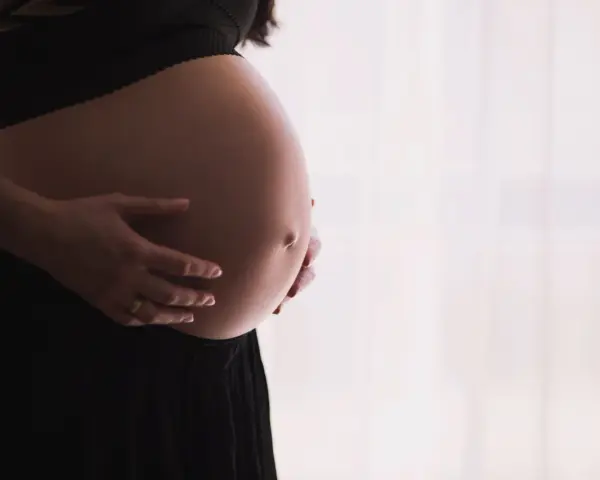 Gravid mage med händer som varsamt håller om den. Kanske funderar hon på proteinpulver gravid för att ge extra näring.