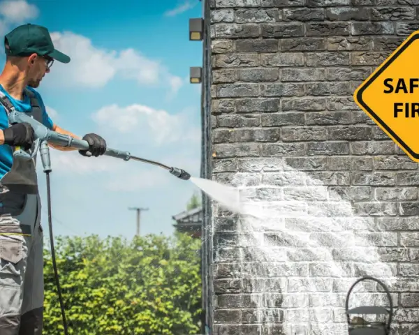Man demonstrates how to use a pressure washer on a brick wall, with a "Safety First" sign visible.