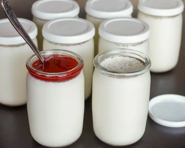 Yaourts maison préparés avec une yaourtière, certains garnis de confiture de fruits rouges. Une recette simple pour un yaourt maison.
