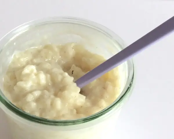 Budino cremoso, profumato alla vaniglia, come quello della ricetta della nonna, pronto per essere gustato con un cucchiaino viola.