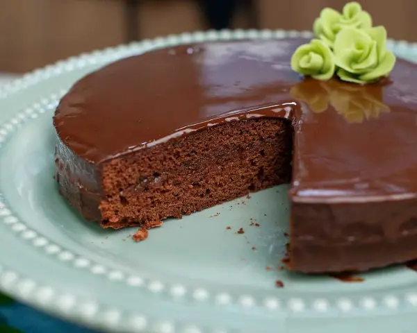 En saftig chokladkaka med blank glasyr, perfekt för ett sachertårta recept. Garnerad med gröna marsipanrosor.