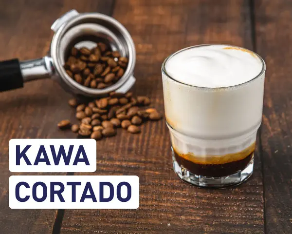 Kawa cortado z mleczną pianką, obok portafilter z ziarnami kawy. Idealny napój na poranek.