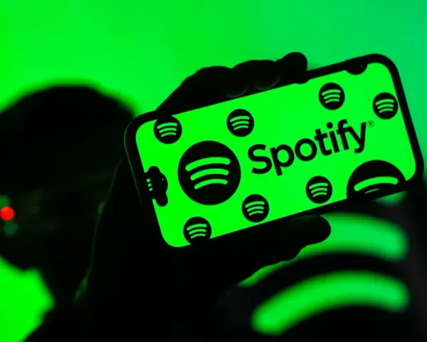 Dłoń trzyma smartfon z zielonym ekranem, na którym widnieje logo Spotify. Użytkownik cieszy się doskonałą spotify jakość dźwięku.