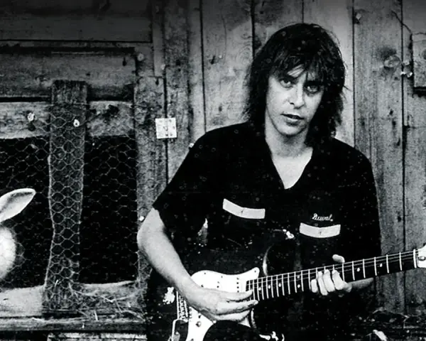 Ein Mann mit Gitarre, im Hintergrund ein Hase im Käfig. Ein Bild, das an den **titel von Rio Reiser** erinnert.