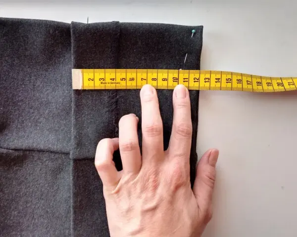 Mierzysz, jak skrócić spodnie ręcznie. Miarka krawiecka pokazuje ok. 11 cm.
