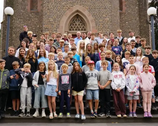 Große Gruppe von Kindern und Jugendlichen vor einer Kirche, die an einem christlichen Ferienlager teilnehmen.