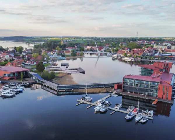 Widok na nowoczesną architekturę i przystań jachtową nad jeziorem. Mazury co warto zobaczyć - idealne miejsce na wypoczynek.