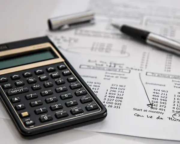 Calculadora y bolígrafo sobre un balance de situación. El balance de situación muestra cifras de inversión y valor al cierre del año.