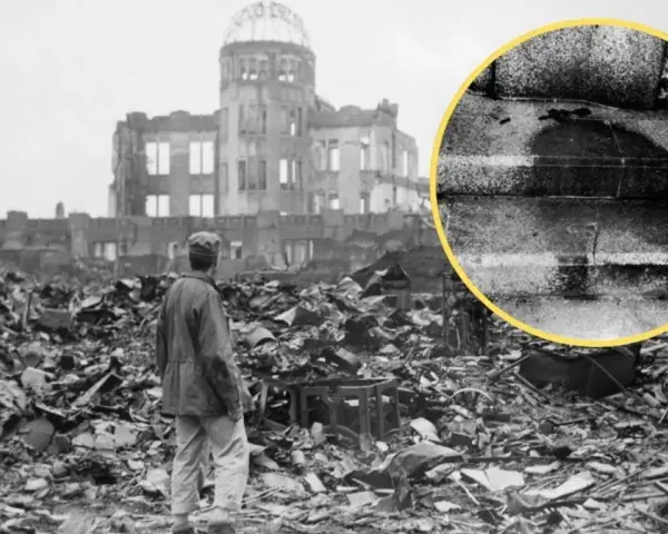 Ruiny w Hiroszimie po bombardowaniu atomowym. W oddali widać zniszczony budynek, a na pierwszym planie stos gruzów i stojącego człowieka. W kółku widoczny ślad po ciele.