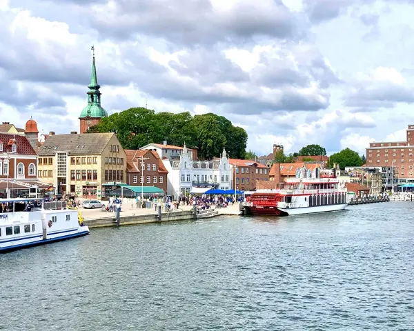 Hafen von Kappeln mit Schiffen und historischen Gebäuden. Entdecken Sie die Kappeln Geheimtipps für Ihren nächsten Urlaub.
