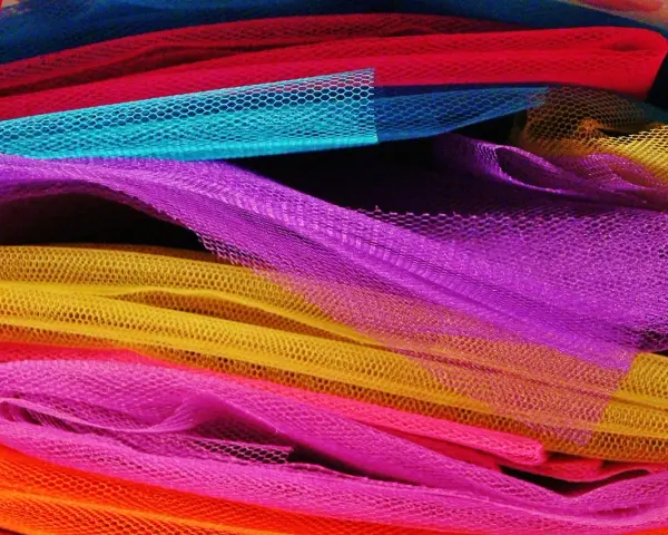Un tas de **tulle** aux couleurs vives : orange, rose, jaune, violet, bleu et rouge.