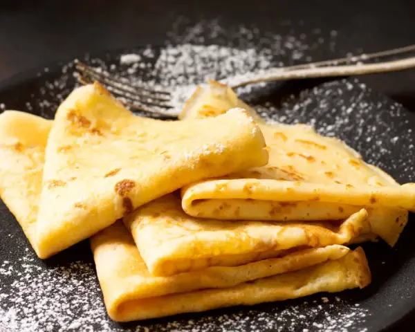Délicieuses crêpes dorées, saupoudrées de sucre glace, prêtes à être dégustées. La pâte à crêpe Thermomix, un jeu d'enfant !