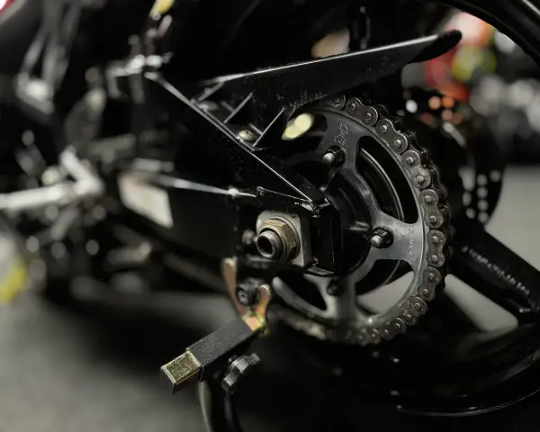 Zbliżenie na tylne koło motocykla, widoczny napęd i łańcuch, gotowy do czyszczenia łańcucha motocyklowego.