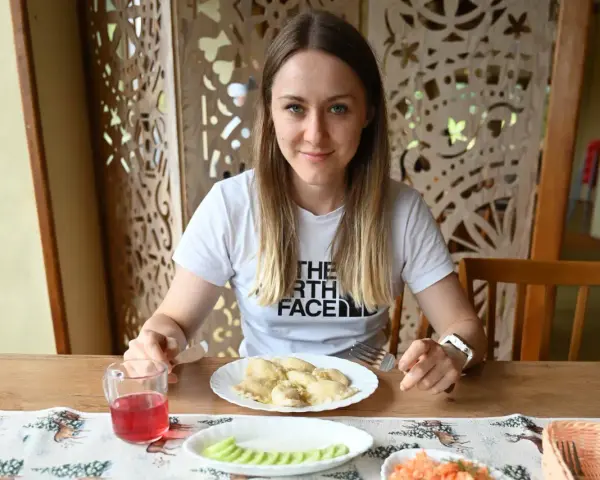 Kobieta przy stole z pierogami i surówką. Posiłek to świetny sposób, jak szybko uzupełnić białko w organizmie.