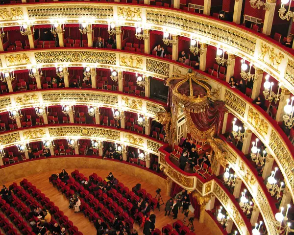 Elegancka loża w teatrze, z czerwonymi aksamitnymi siedzeniami i złotymi zdobieniami, czeka na widzów.