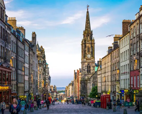Edinburgh's Royal Mile with a clock tower and people walking on a cobblestone street.
