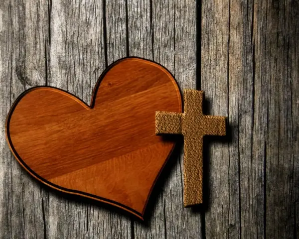 Holzherz und Kreuz auf grober Holzoberfläche. Ein Symbol für Liebe und Glauben, wie in Lukas 23,34.