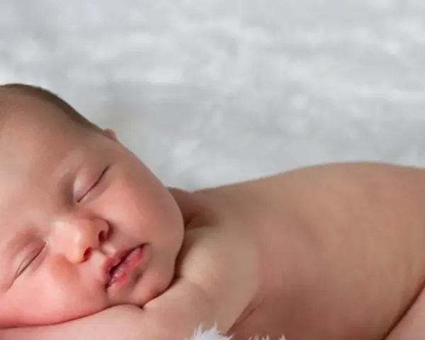 Śpiące, 3 miesięczne dziecko z delikatnymi włoskami, wtulone w miękkie futerko.