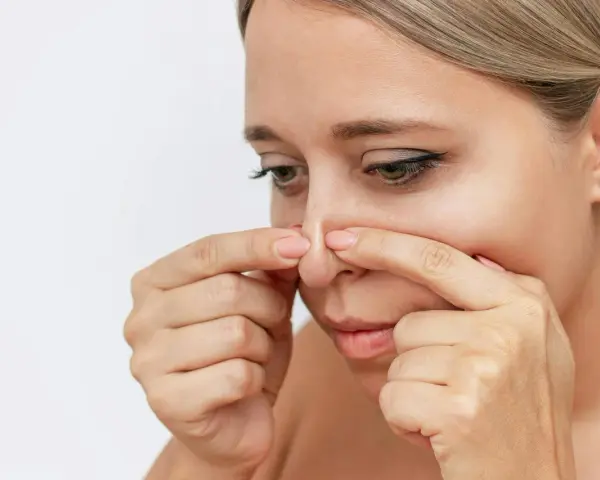 Kvinna undersöker sin näsa, kanske för pormask behandling.