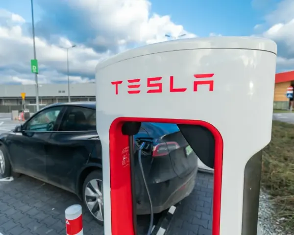 Czarna Tesla podłączona do ładowarki Supercharger.
