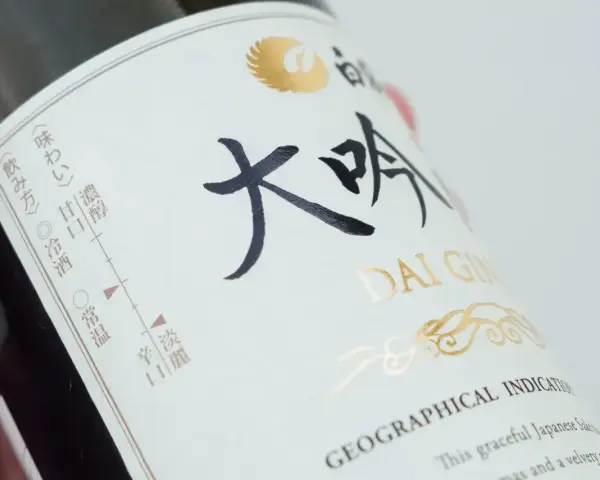 Butelka sake z napisem "DAI GIN". Na etykiecie widać skalę smaku i temperatury podania.