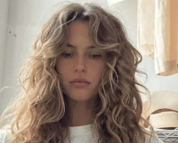 Chica con pelo rizado y flequillo desfilado, inspirador para tipos de flequillo para pelo rizado.