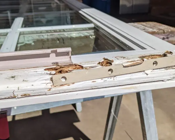 Damaged wood window frame, showing rot and peeling paint, indicating a need for wood window repair.
