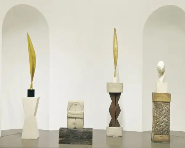Rzeźby inspirowane twórczością **Constantin Brâncuși**: złoty liść, kamienna postać, drewniany rdzeń i biała głowa.
