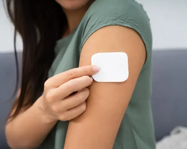 Kobieta przykleja plaster antykoncepcyjny. Przed użyciem warto zapoznać się z przeciwwskazaniami.