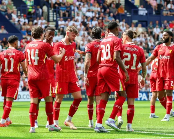 Piłkarze Liverpoolu, mistrzowie Anglii, świętują na boisku. Widać numery 11, 14, 8, 38, 21 i 2.