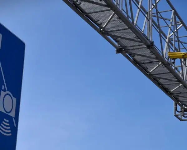Niebieski znak informuje o odcinkowym pomiarze prędkości S7. Nad drogą widać konstrukcję z żółtą kamerą.