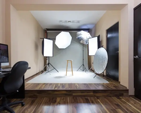 Gotowy pokój fotografa z lampami, statywami, taboretem i komputerem.