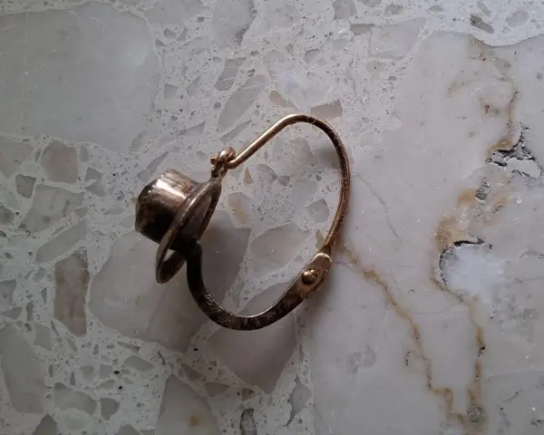 Orecchino d'oro con pietra scura, un po' consumato dal tempo, segno che l'oro si ossida.