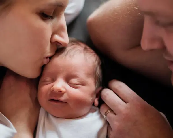 Mutter küsst ihr Neugeborenes, Vater schaut liebevoll zu. Diese Momente sind unbezahlbar, auch nach 1000 Tagen.