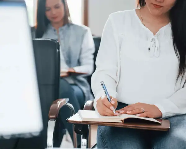 Estudiantes toman notas en clase. Se registran los gastos de formación en la cuenta contable.