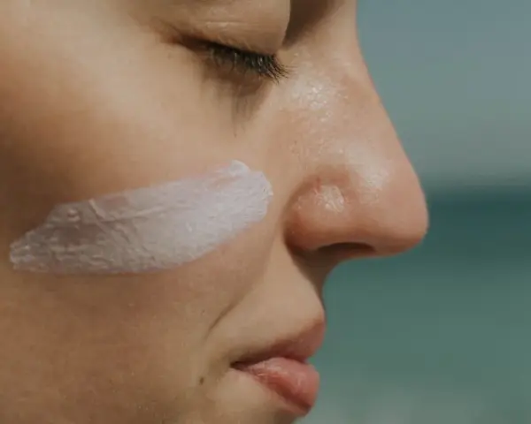 Rostro de mujer con una pincelada de crema solar biodegradable en la mejilla.