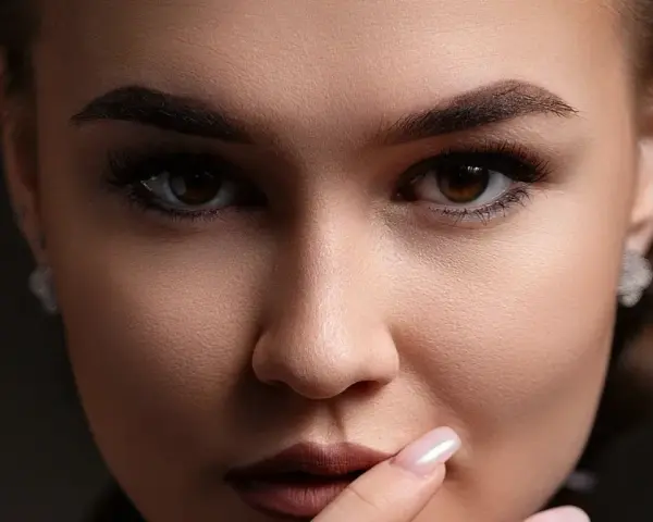 Un gros plan sur le visage d'une femme, ses sourcils parfaitement dessinés après une séance d'épilation.