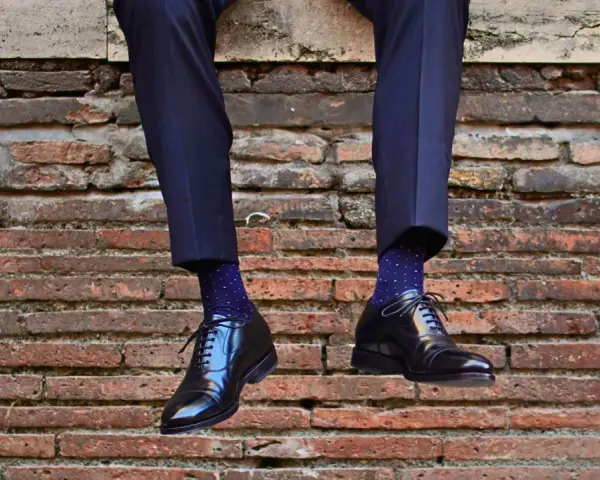 Uomo con calzini blu a pois bianchi e scarpe nere lucide. Un perfetto abbinamento calzini scarpe uomo per un look elegante.