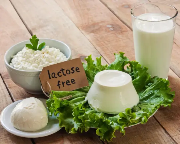 Serek wiejski, kulka mozzarelli i ser w kształcie stożka na sałacie, obok szklanki mleka. Etykieta głosi "lactose free", co oznacza brak laktozy.