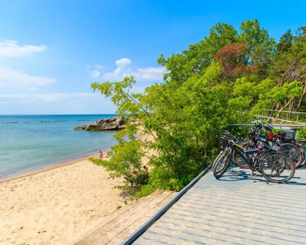Rowerzyści odpoczywają na plaży, a ich rowery czekają na dalszą podróż po malowniczych pomorskich trasach rowerowych.