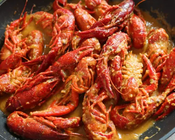 Un delicioso cangrejo de río en una sartén, bañado en una cremosa salsa. ¡Un manjar listo para disfrutar!